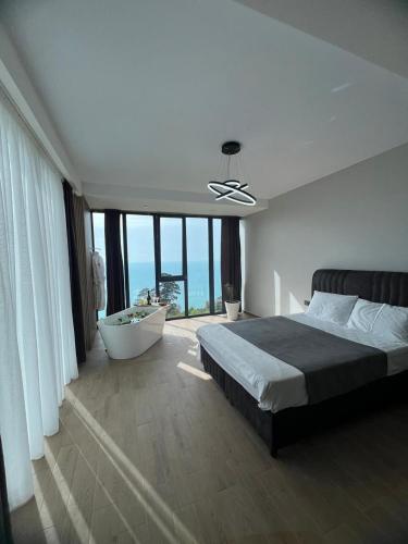 a bedroom with a bed and a bath tub and windows at Villa Deluxe Kvariati in Kvariati