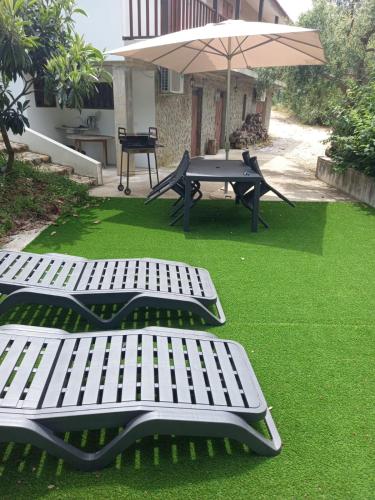 two picnic tables and an umbrella on a lawn at Casa Vale Nicolau in Arganil