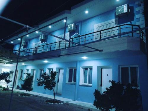 a blue building with a balcony at night at Manas Rooms in Dhërmi