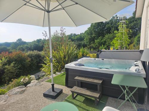 a hot tub with an umbrella and a bench at Le Coucher de Soleil Spa in Bessens