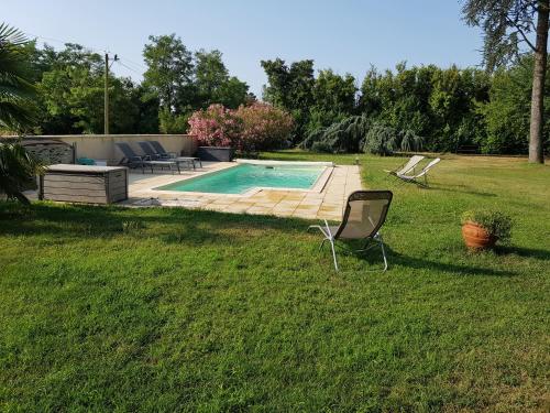 a yard with a swimming pool and a chair in the grass at EPICEAH Loft à la campagne à 10 mn de Valence in Valence