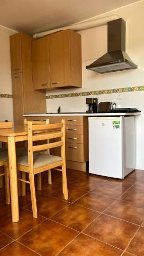 a kitchen with a wooden table and a white refrigerator at Apartamentos el Olivo in Trias
