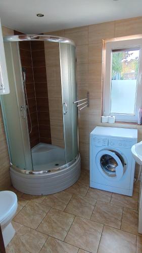 a bathroom with a shower and a washing machine at Domek Olivia Wilkasy, Mazury in Wilkasy