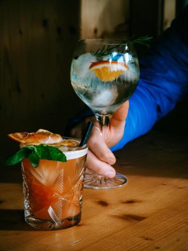 a person holding a wine glass and a drink at Locanda La Baita in Santo Stefano di Cadore