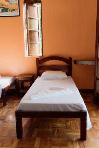 a bed in a room with an orange wall at Pousada Recanto da Ladeira in Paraty