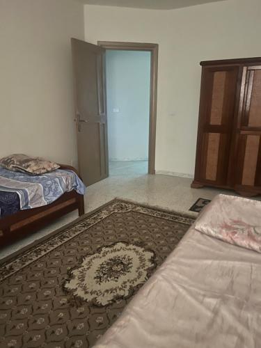a room with two beds and a door with a rug at Appartement nasria in Sfax