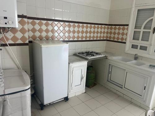 a kitchen with a stove and a sink and a refrigerator at Appartement nasria in Sfax