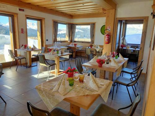 a restaurant with wooden tables and chairs and windows at Locanda La Baita in Santo Stefano di Cadore