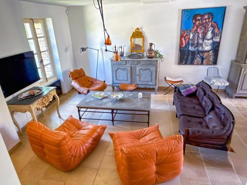un salon avec des chaises orange et une table dans l'établissement Villa de vacances à Gordes avec piscine, La Bastide de Léa, à Gordes
