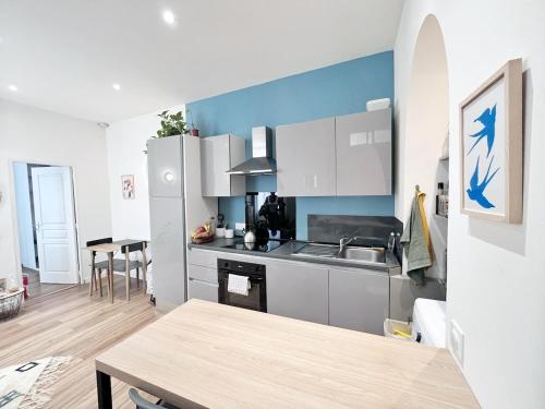 une cuisine avec des armoires blanches et une table à l'intérieur dans l'établissement Charmant 2 pièces Nice Centre à deux pas de la gare, à Nice