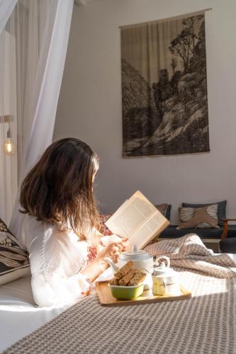 a woman reading a book on a bed with a tray of food at The Old School in McGregor