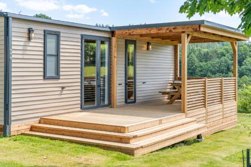 a tiny house with a deck and a pergola at Maison de Vacances - Parc de Vacances Papillon Bouillon in Bouillon