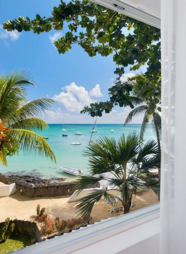 a window view of a beach with boats in the water at Le Beachclub in Pereybere