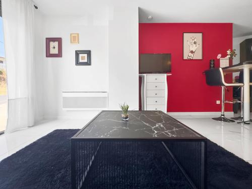 - un salon avec une table et un mur rouge dans l'établissement Studio BAROK proche autoroute, plages et attractions, Wifi - TV, calme, à Bessan