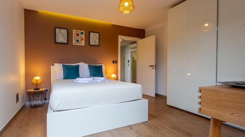 a bedroom with a large white bed with blue pillows at The Jolie - A Retreat in the City in an Entire House in Funchal
