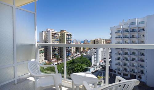 a balcony with white chairs and a view of a city at Sandos Griego in Torremolinos