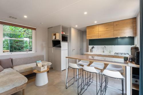 a kitchen and living room with a counter and stools at Maison de Vacances - Parc de Vacances Papillon Bouillon in Bouillon
