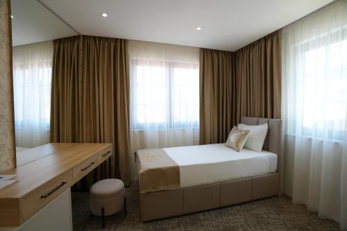 a bedroom with a bed and a desk and window at Avdissons Hotel in Prizren