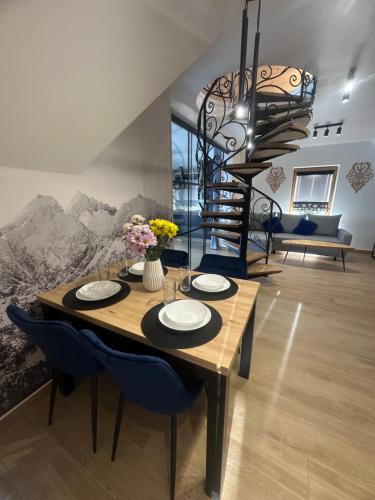 a dining room with a table and a spiral staircase at Wierchowe Zacisze in Bukowina Tatrzańska