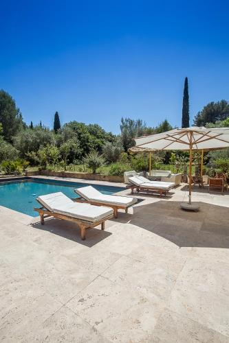 une piscine avec des bancs et un parasol à côté dans l'établissement Villa Des oliviers, au Beausset