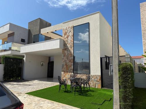 a house with four chairs on a lawn at Casa Tibau in Tibau