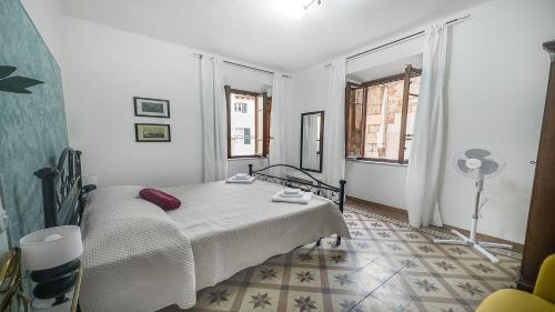a white bedroom with a bed and a fan at Casa di Olga - Historical Apartment inside the Walls in Lucca