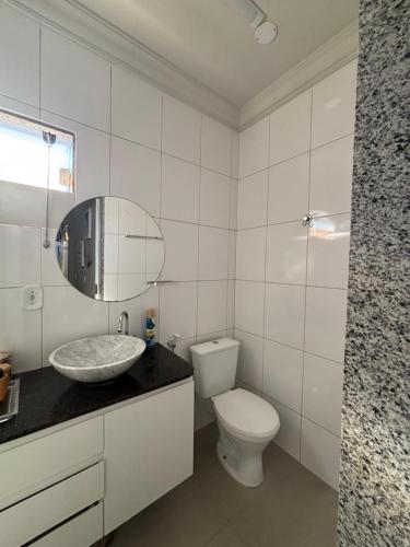 a white bathroom with a sink and a toilet at Apartamento mobiliado in Cachoeiro de Itapemirim