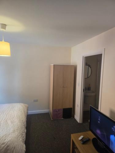 a bedroom with a bed and a dresser and a television at Ensuite room in Wolverhampton city center in Wolverhampton
