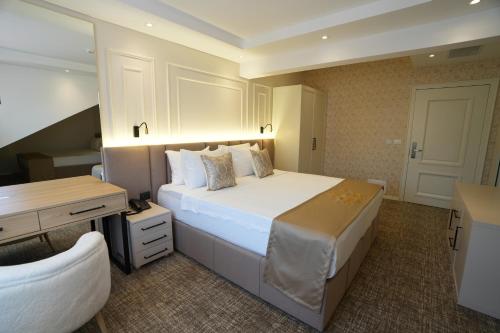 a bedroom with a large white bed and a desk at Avdissons Hotel in Prizren