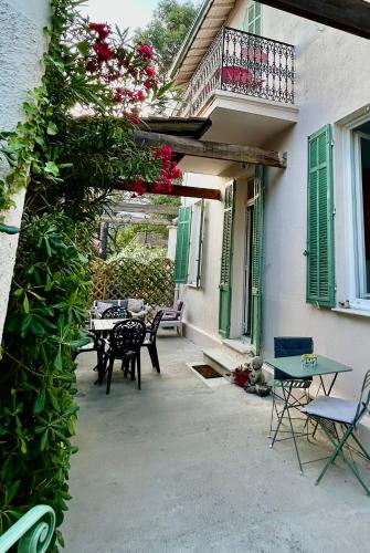 a patio with tables and chairs and a balcony with flowers at Oasis de verdure en centre-ville - jacuzzi privé in Mandelieu-la-Napoule
