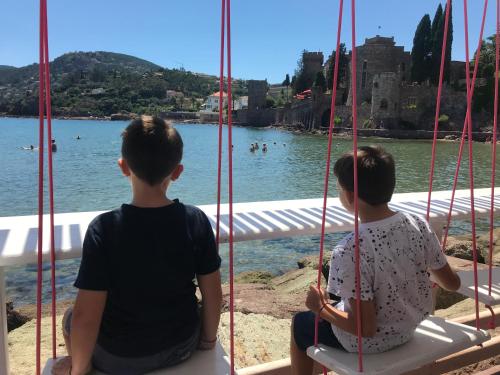 two children sitting on a bench looking at the water at Oasis de verdure en centre-ville - jacuzzi privé in Mandelieu-la-Napoule