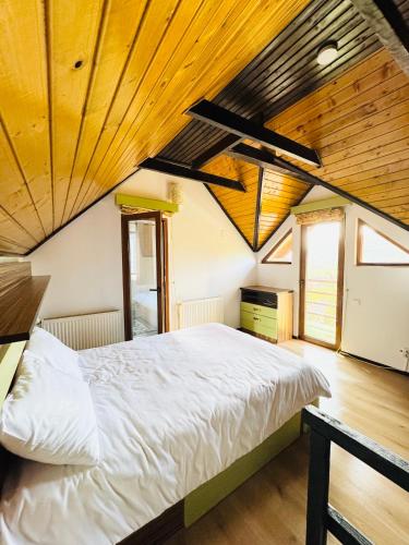 a bedroom with a white bed in a room with wooden ceilings at Cabana Lapina in Vatra Dornei