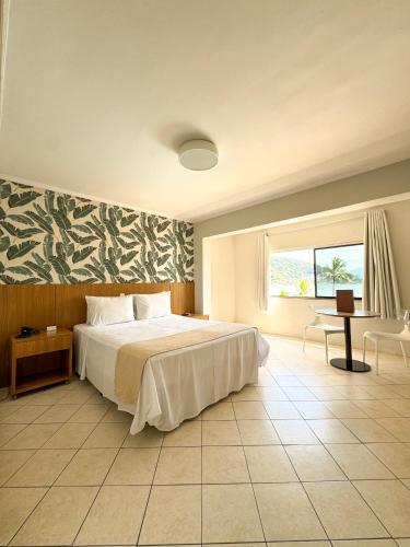 a bedroom with a bed and a desk and a window at Ilha Porchat Hotel in São Vicente