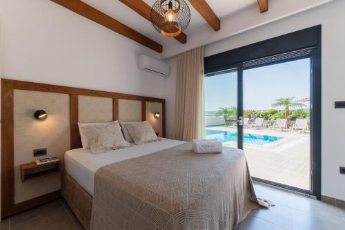 a bedroom with a bed with a view of a pool at Prasonisi Villas in Kattavía