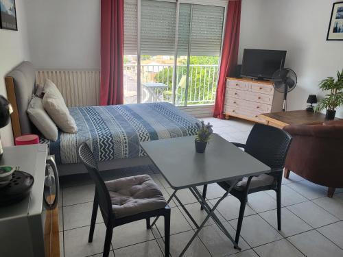 une chambre avec un lit, une table et des chaises dans l'établissement Residence d'Anjou - Grand studio avec balcon et parking privatif, à Perpignan