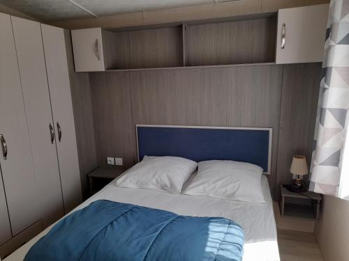 - un lit avec une tête de lit bleue dans une chambre dans l'établissement le mobile home Le Victory situé au Camping Le Rio, à Noyelles-sur-Mer