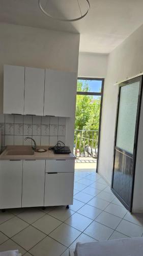 una cucina con mobili bianchi e vista sul patio di Neta apartments a Velipojë