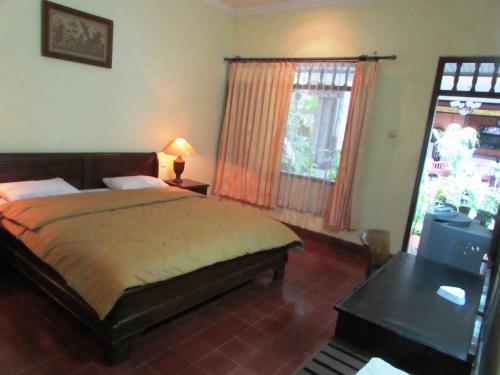 a bedroom with a bed and a desk and a window at Griya Ayu Inn in Sanur