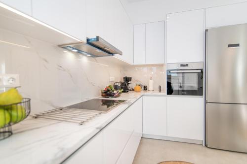 a kitchen with white cabinets and a stainless steel refrigerator at eleni luxury apartment in Tinos Town