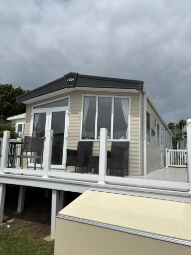 a mobile home with a porch and a deck at 2 Bed, 2 Bathroom, modern Caravan with Sea views! in Lytchett Minster