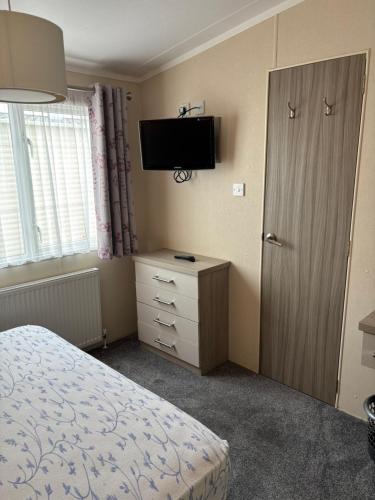 a bedroom with a bed and a flat screen tv at 2 Bed, 2 Bathroom, modern Caravan with Sea views! in Lytchett Minster