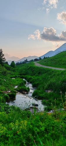 a river in a green field with mountains in the background at La Dimora di Beatrice in Santa Brigida