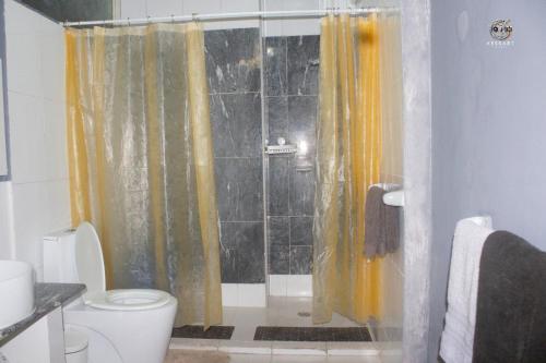 a bathroom with a shower with yellow curtains and a toilet at Citycomfortluanda in Luanda