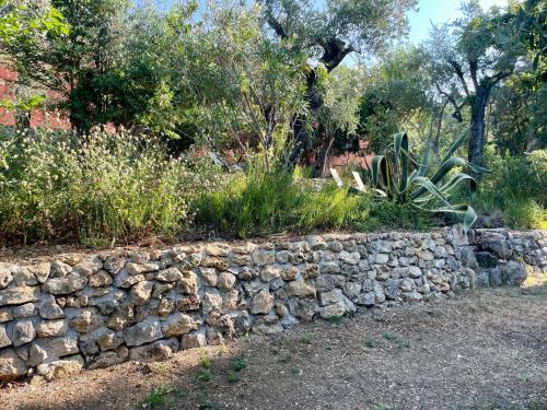 a stone retaining wall in front of a garden at Villa Les Chants Vallonnés in Spéracèdes