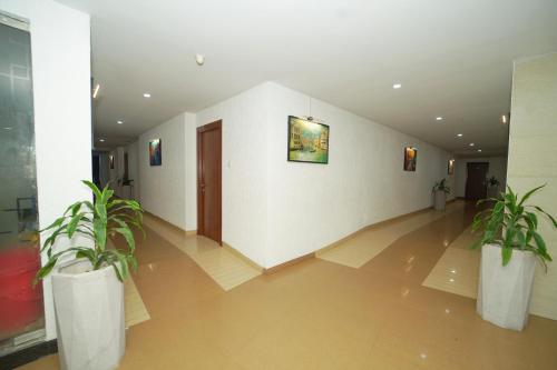 a hallway with two potted plants in a building at Hotel Occassia Bliss Miyapur in Lingampalli