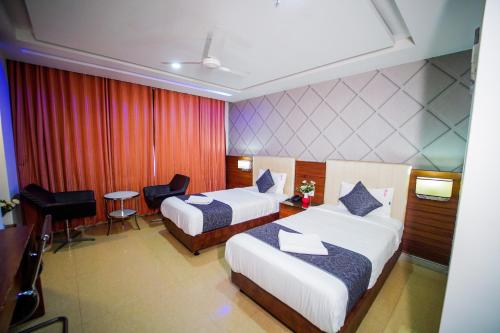 a hotel room with two beds and a desk at Hotel Occassia Bliss Miyapur in Lingampalli