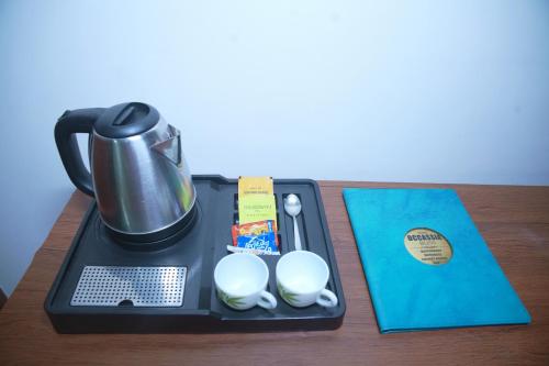 a tray with a coffee maker and a tea kettle at Hotel Occassia Bliss Miyapur in Lingampalli