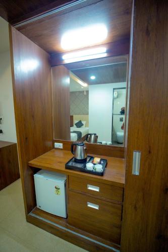 a bathroom with a mirror and a tea kettle on a counter at Hotel Occassia Bliss Miyapur in Lingampalli