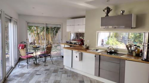 une cuisine avec des armoires blanches et une table avec des chaises dans l'établissement De plain pied, à Sète