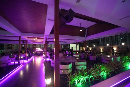 a restaurant with purple lighting and people sitting at tables at Hotel Occassia Bliss Miyapur in Lingampalli